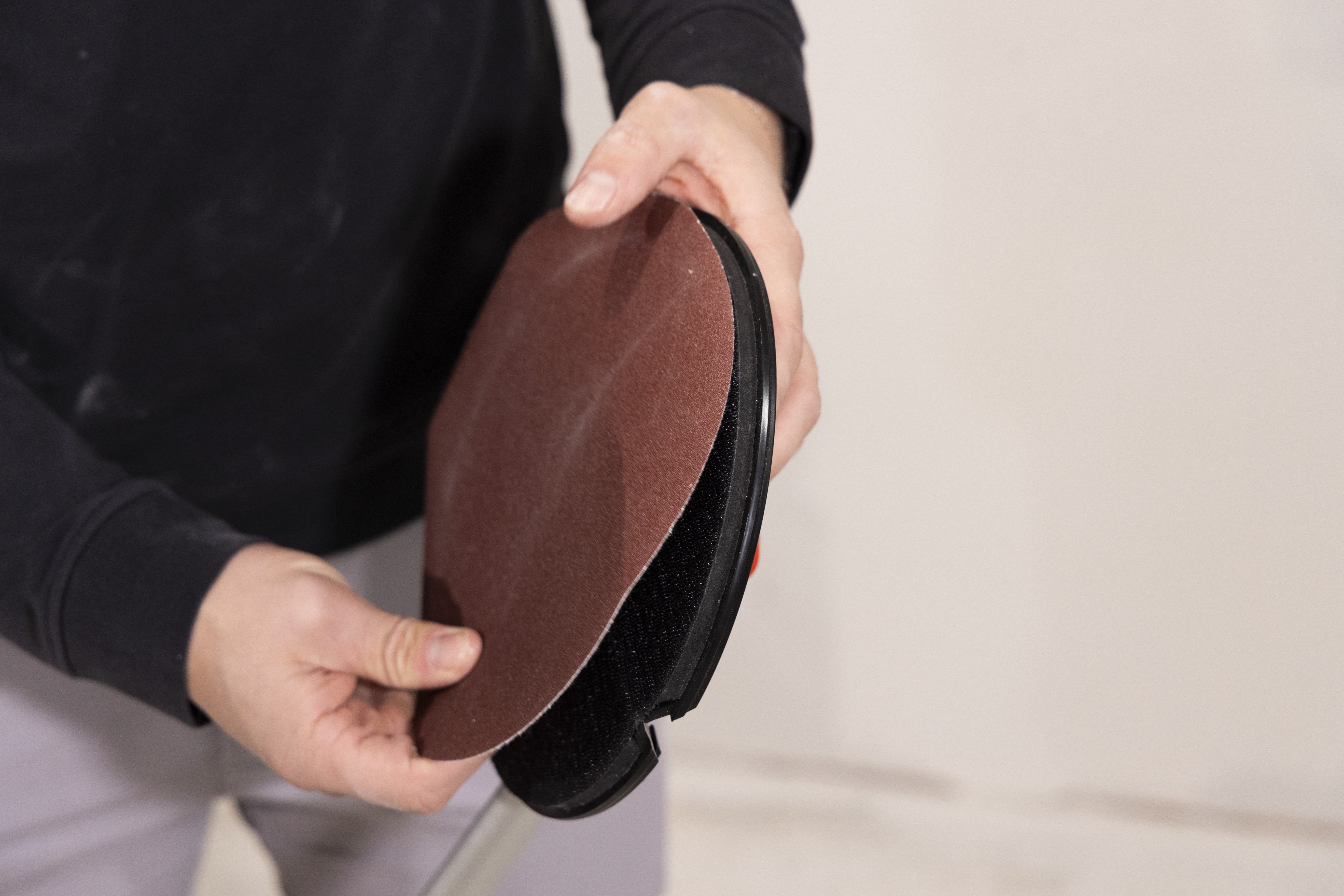 man attaching a sheet of sandpaper to the folding radial sander head
